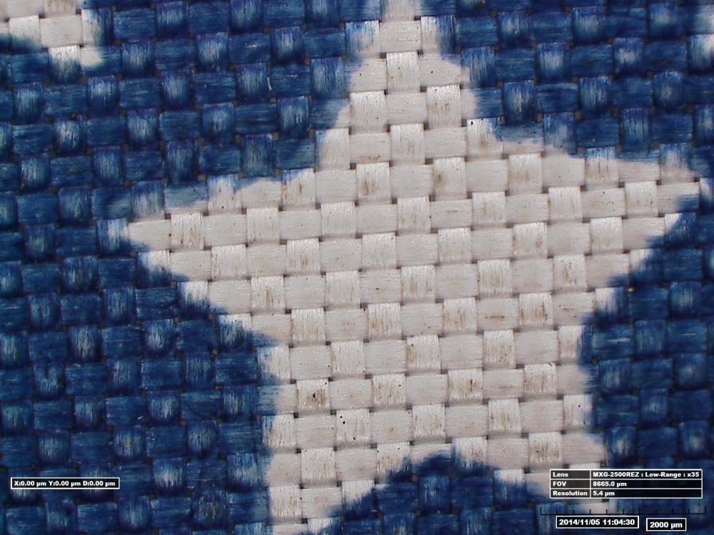 Close-up view of a cover used over an oxygen purge system. The weaved fabric shows mild discoloration on the blue sections and lunar dust on the white star section.