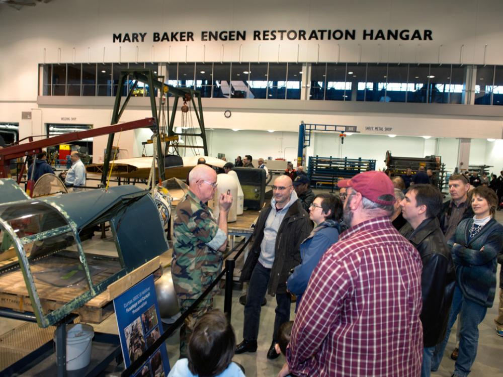 Museum specialists give a presentation to visitors inside the Museum's restoration hangar.