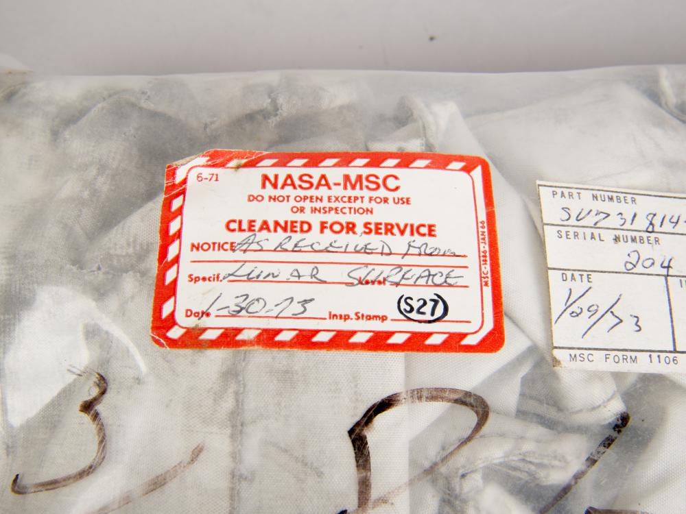 Cover of a sealed white-colored fabric cover for an oxygen purge system. One red and white tag states that the cover has been "cleaned for service" and is not to be opened "except for use or inspection".