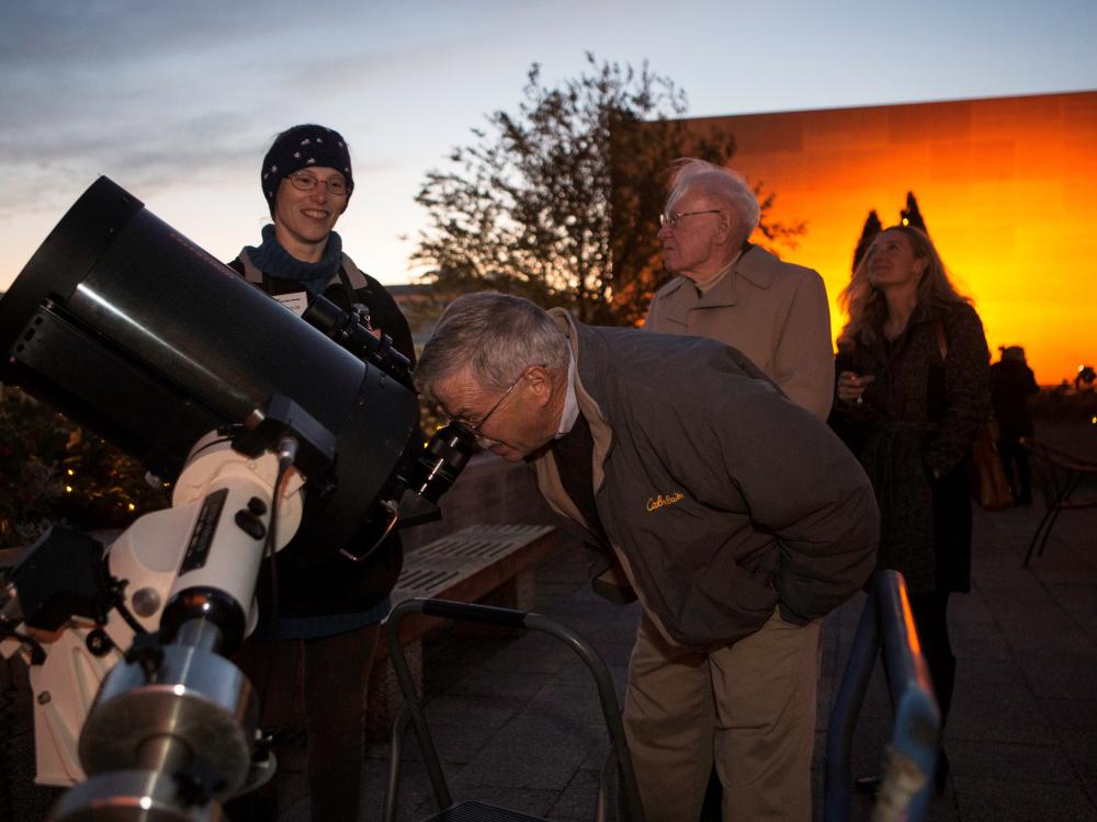 Museum staff assist in allowing visitors to use telescopes at a Museum event.