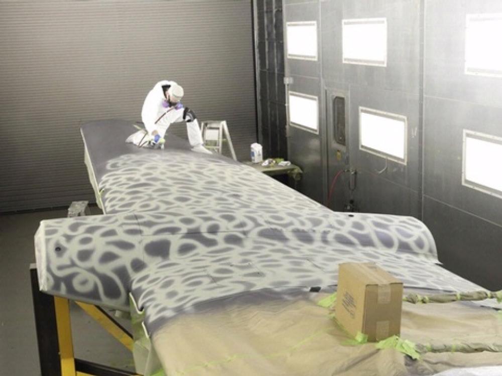 A museum specialist uses white paint to recreate the original pattern of paint on an aircraft during its restoration process.