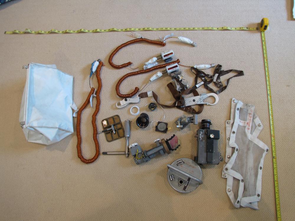 A white fabric stowage bag on the left with its respective items on the right. Items include various equipment and tools.