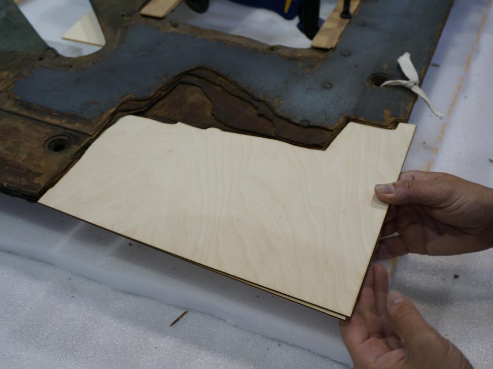 A Museum staff member places a second layer of plywood intended for use in repairing holes in a World War II era aircraft.