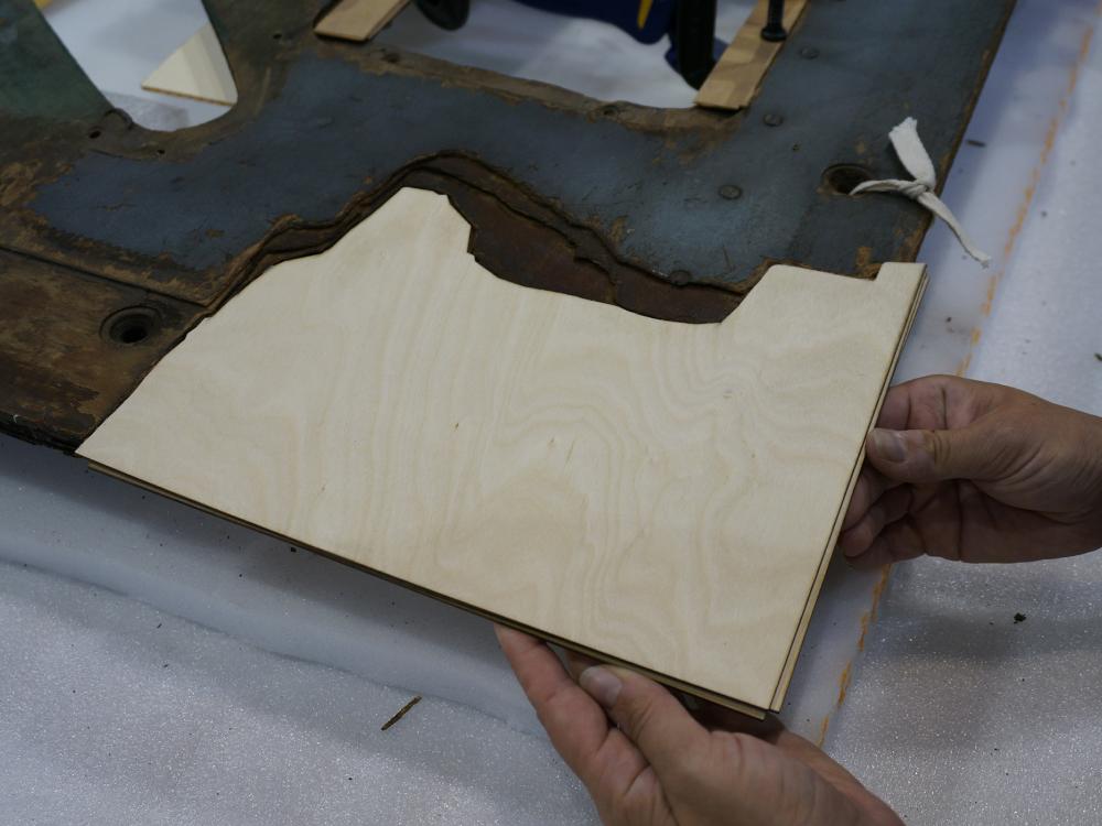 A Museum staff member places a third layer of plywood intended for use in repairing holes in a World War II era aircraft.