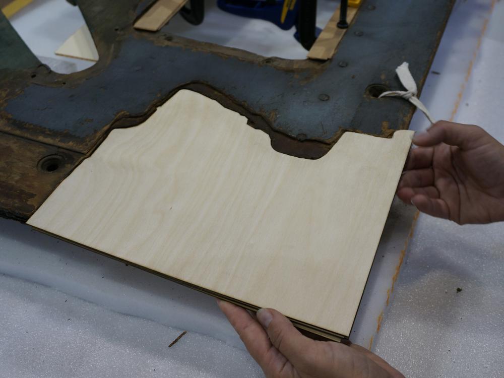 A Museum staff member places a fourth layer of plywood intended for use in repairing holes in a World War II era aircraft.