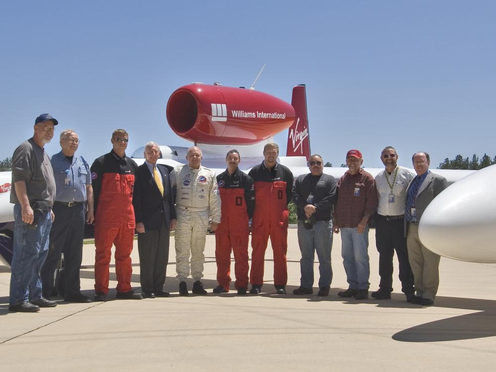 A group of eleven people stand in front of a red and white aircraft at the Udvar-Hazy Center.