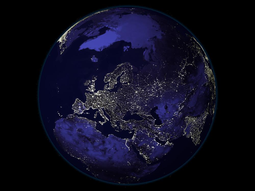 A satellite view of Earth during nighttime hours, with a focus on Europe and Northern Africa which has many lights visible from space.