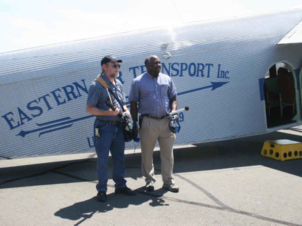 Two Smithsonian employees stand in front of white Ford Tri-Motor aircraft.