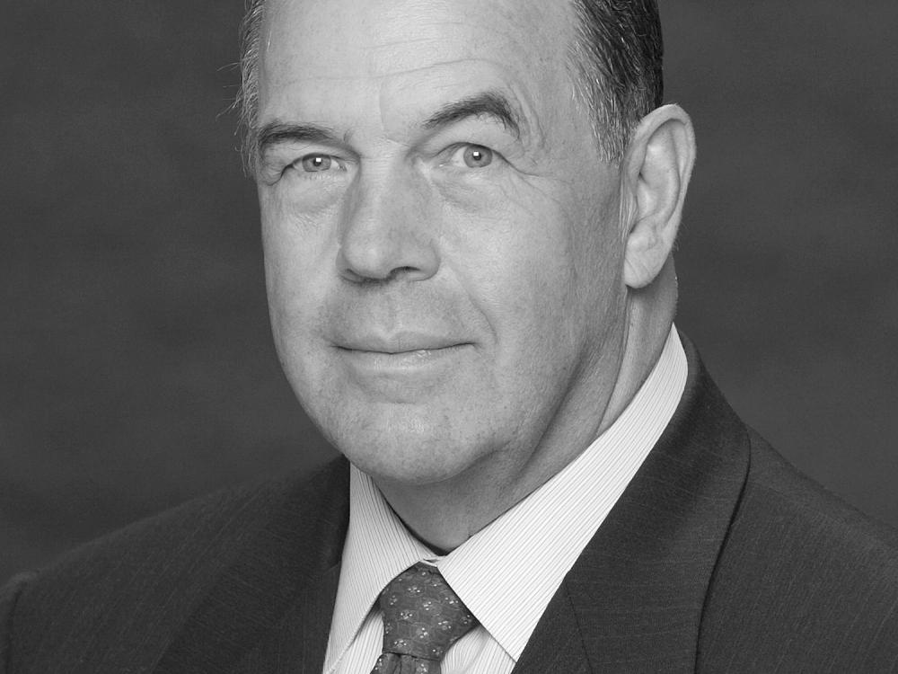 Black and white portrait of David C. Hurley, a former president of the National Air and Space Museum Board, who smiles towards the subject