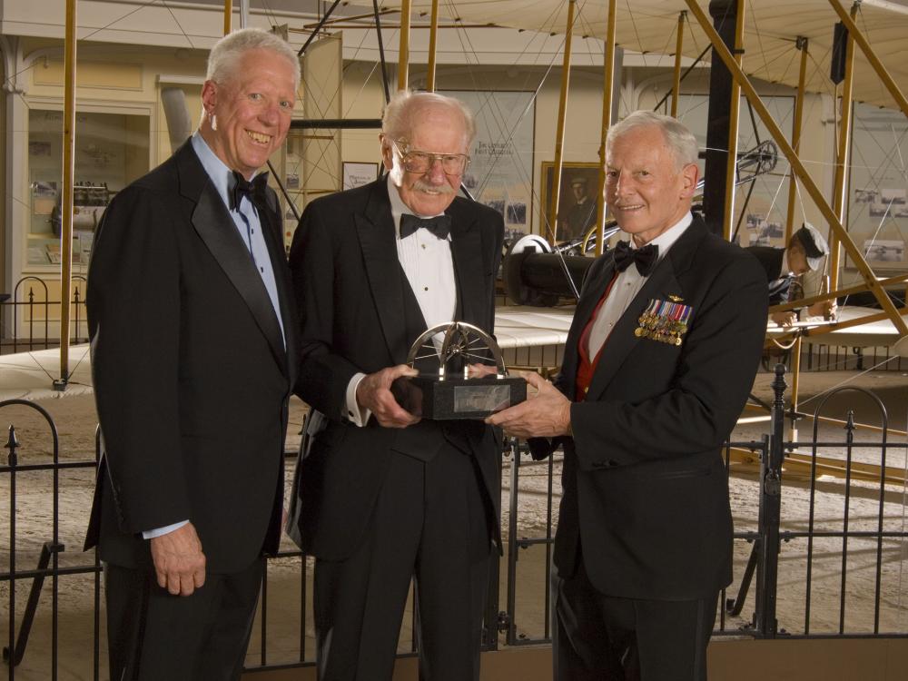 Former Museum Director Jack Dailey, pilot Robert "Bob" Hoover, and Awards Master of Ceremonies David Hartman stand together at an awards ceremony.