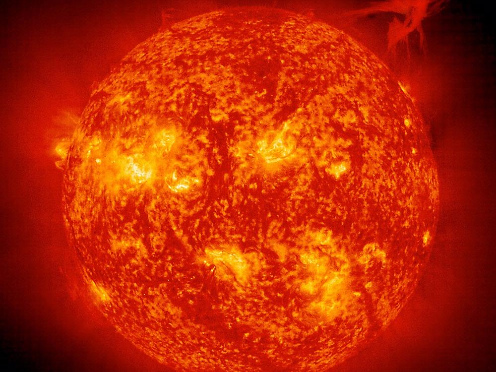 A prominence, a cloud of cool, dense plasma, erupts and escapes the sun's atmosphere in the upper right quadrant of the photo.