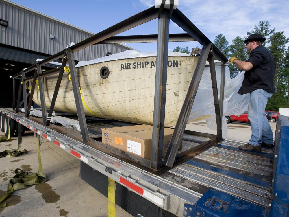 A wooden lifeboat sits on the back section of a vehicle