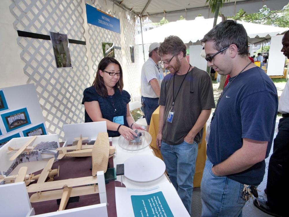 A woman displays an exhibit to patrons at the Folklife Festival.