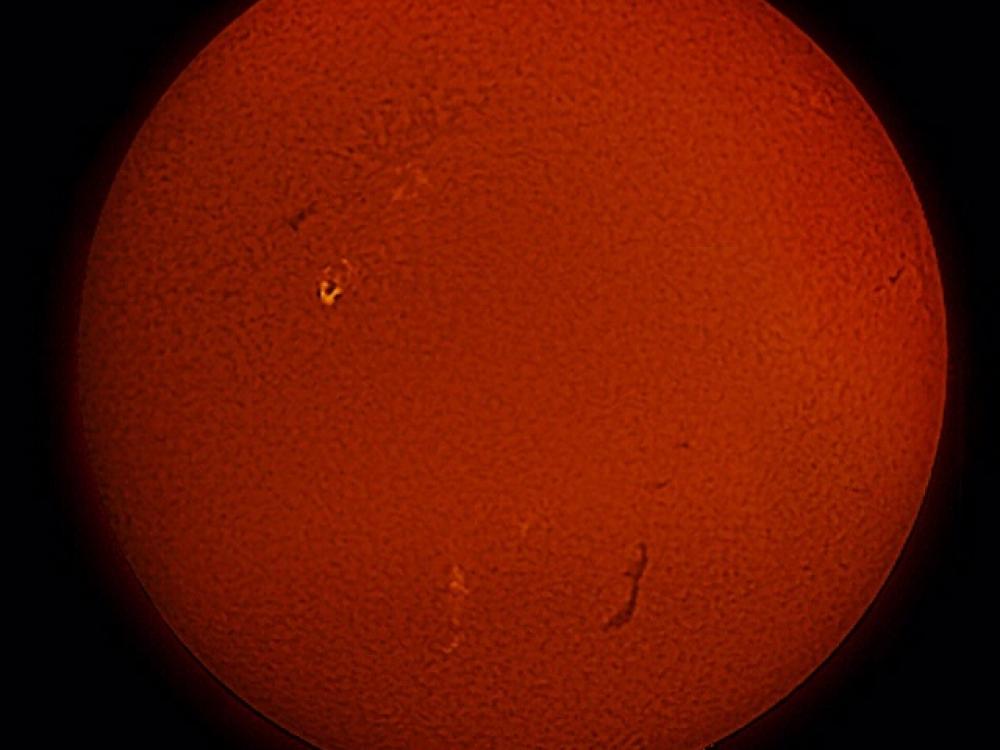 Disc view of full sphere of Sun with a brighter patch of gases seen from the telescope on the left side.