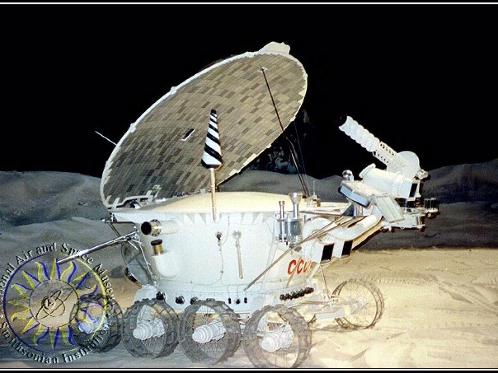 A white robotic spacecraft with a oblong-shaped base. A circular solar panel and multiple probes and cameras are attached to the base.