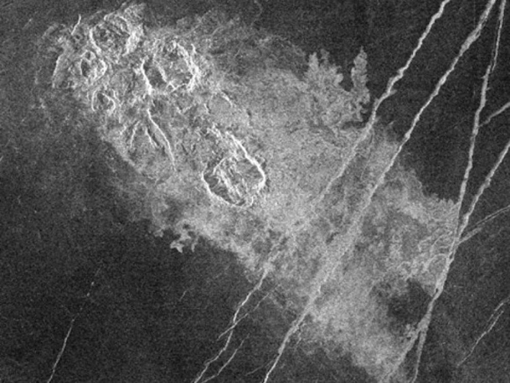 A satellite view of a set of impact craters on the surface of Venus, which looks lighter in color compared to the other sections visible.