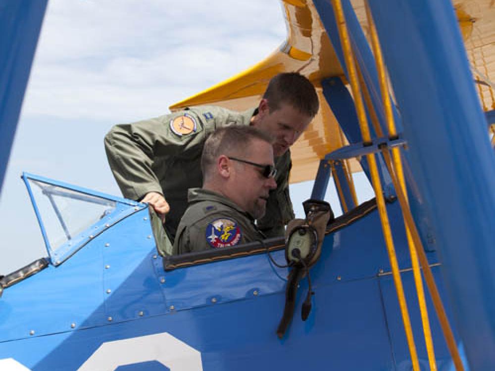 Capt. Matt Quy shows modern military curator Dik Daso how to use safety belts in the cockpit