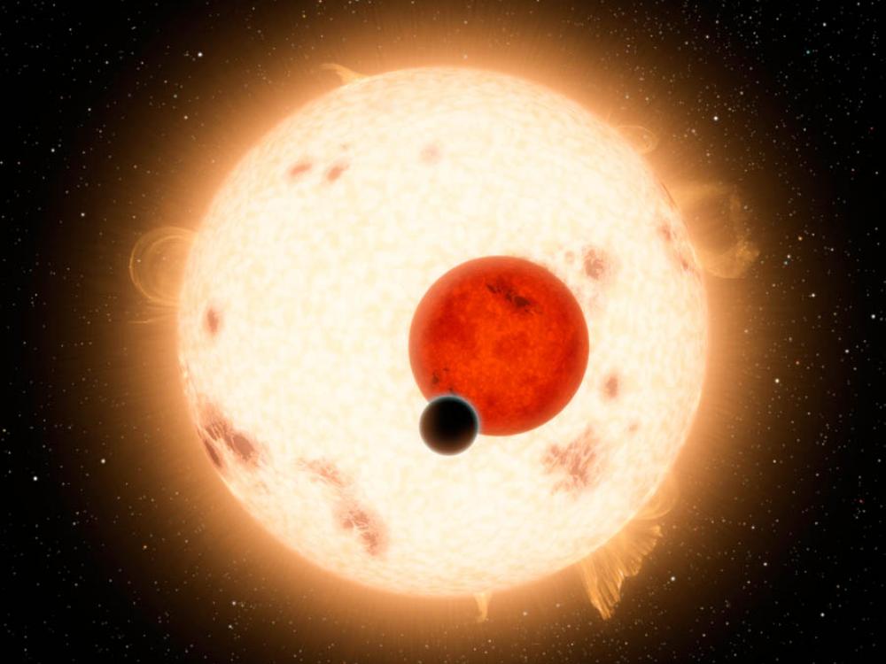 An illustration of a small planet in front of a smaller red dwarf star and a larger yellow star.