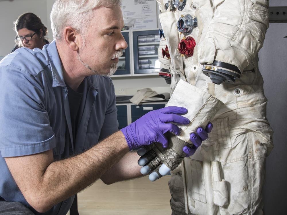 Exhibits Specialist Adam Bradshaw with the white beta cloth lunar spacesuit 