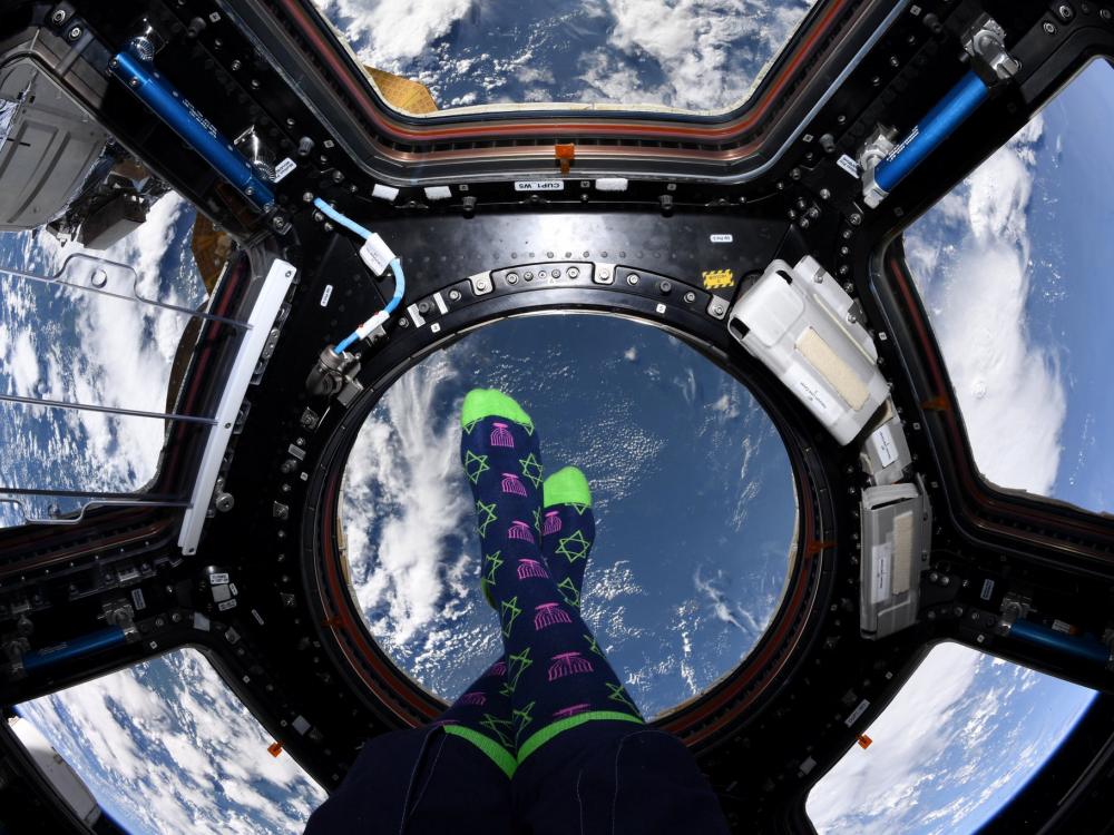 Floating above the Earth, an astronaut posts a picture of her feet in Hanukkah socks.