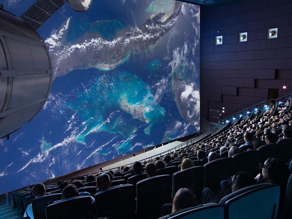 Shot of an IMAX movie screen with viewers seated in the theater. 