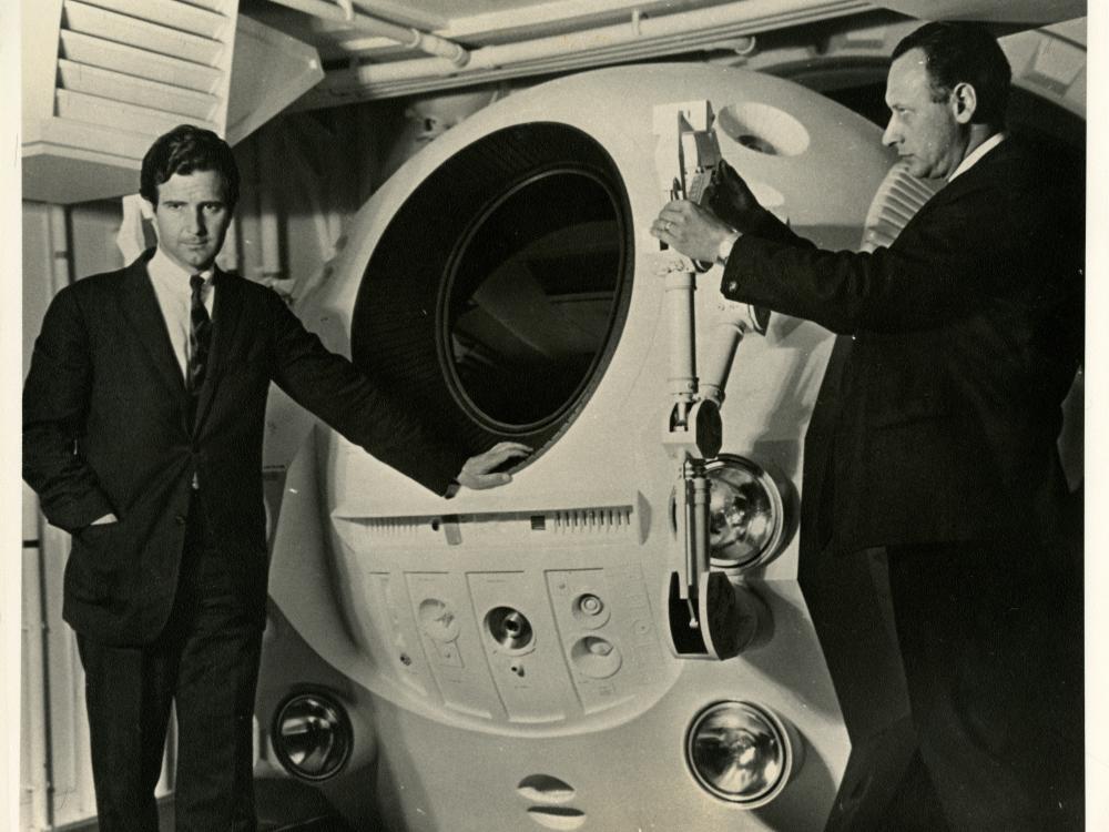 Frederick I. Ordway III (left) and Harry Lange (right) pose with an EVA Pod in the Discovery One pod bay interior set of the motion picture 2001: A Space Odyssey 