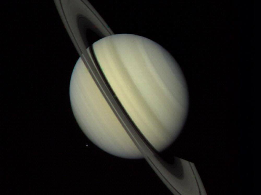 Saturn, a yellow gas planet with large rings surrounding the sphere, as seen via disc view