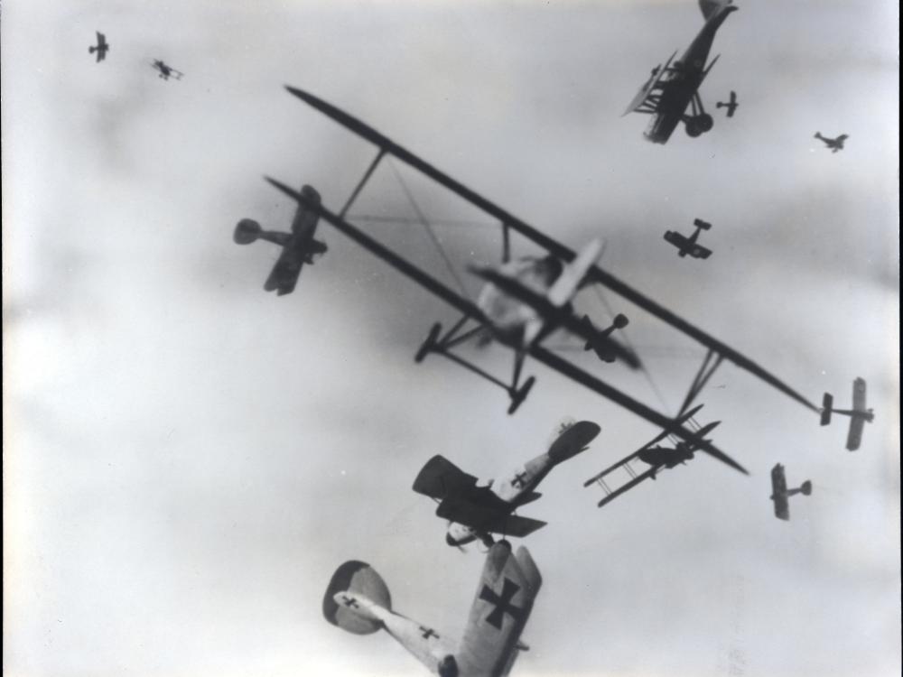 Black and white photo of airplane in the sky. 