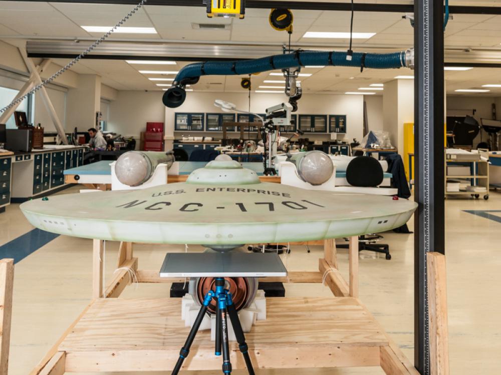 A dish-shaped starship studio model is placed on a surface prior to undergoing X-rays.