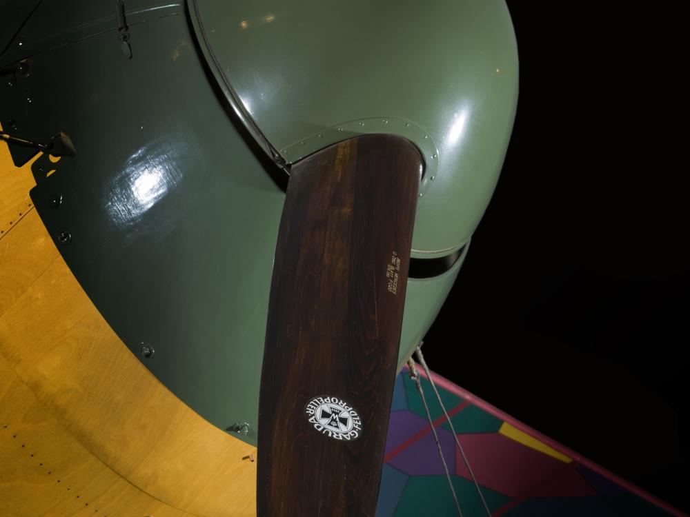 Closeup of green nose of aircraft and wooden propeller