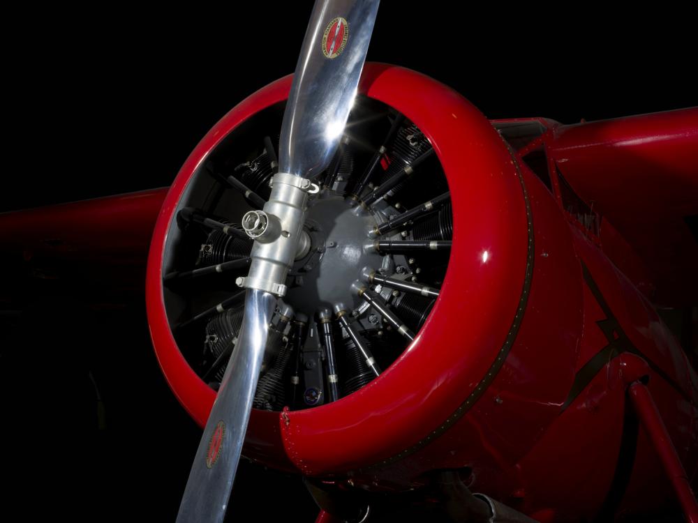 Front engine and silver single-blade propeller on red Amelia Earhart Lockheed Vega 5B aircraft