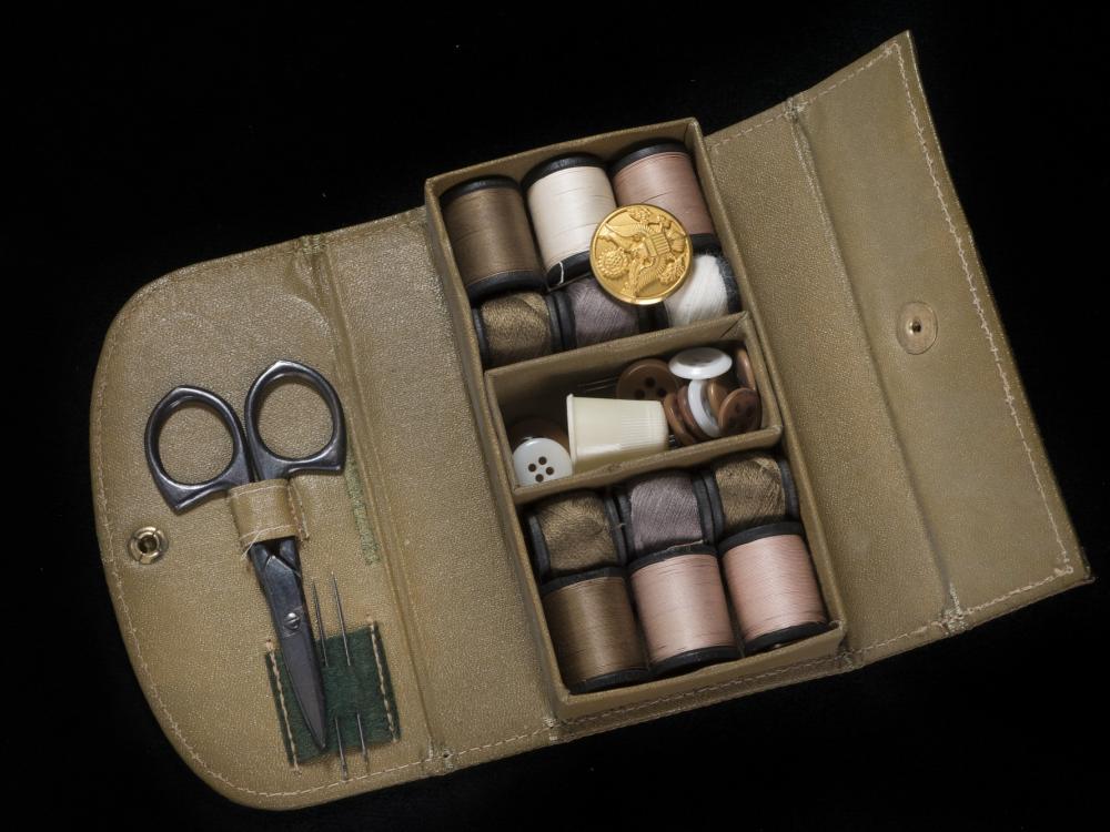 Rectangular box with thread spools, needles, buttons, and scissors