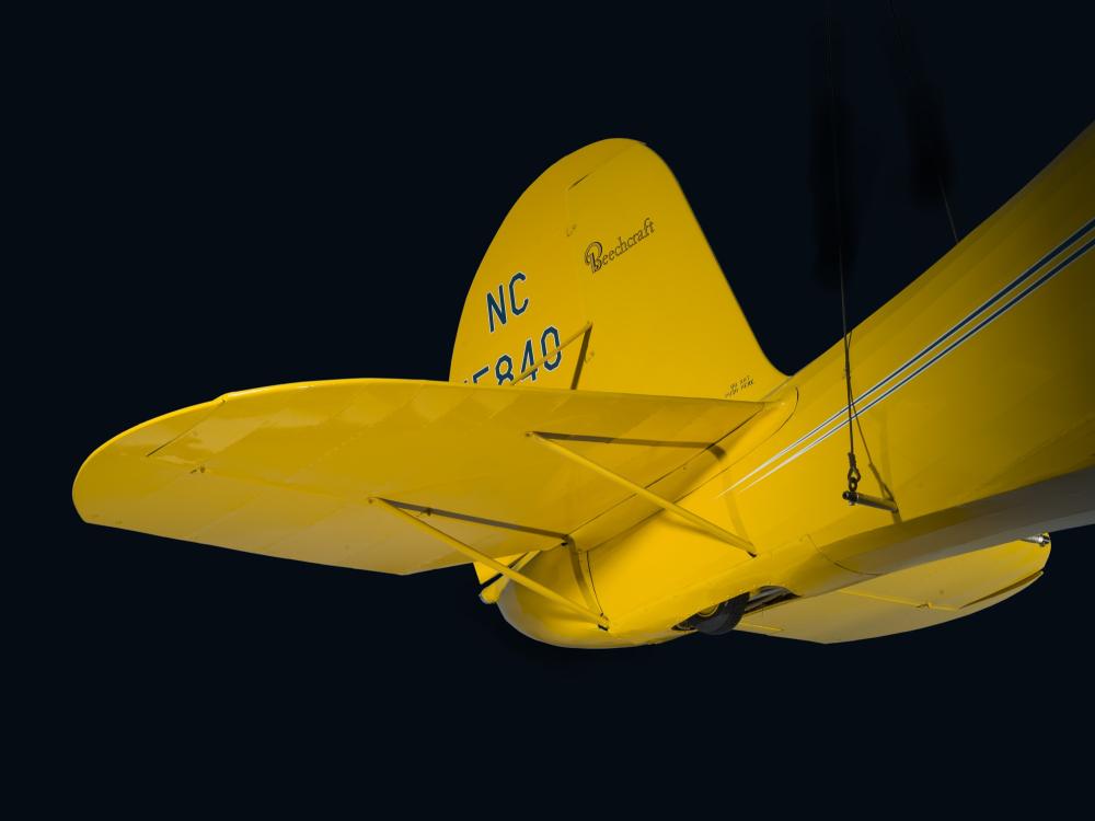 View of the vertical and horizontal stabilizers on tail of yellow Staggerwing aircraft