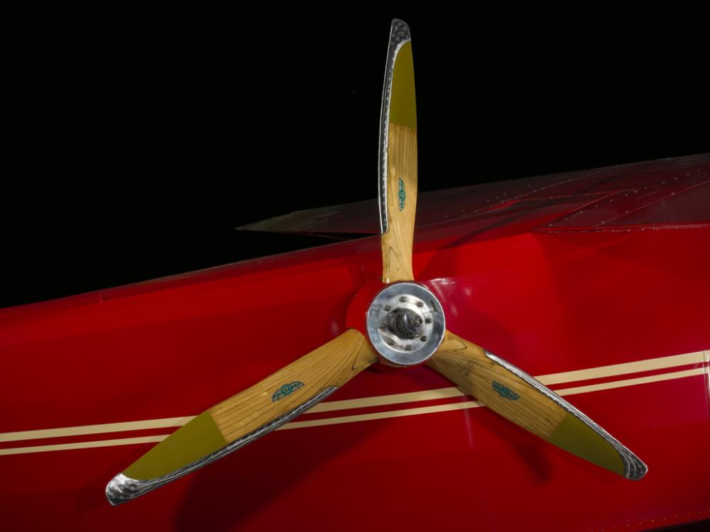 Close up image of a wood airplane propeller. The propeller is attached to a air plane. 