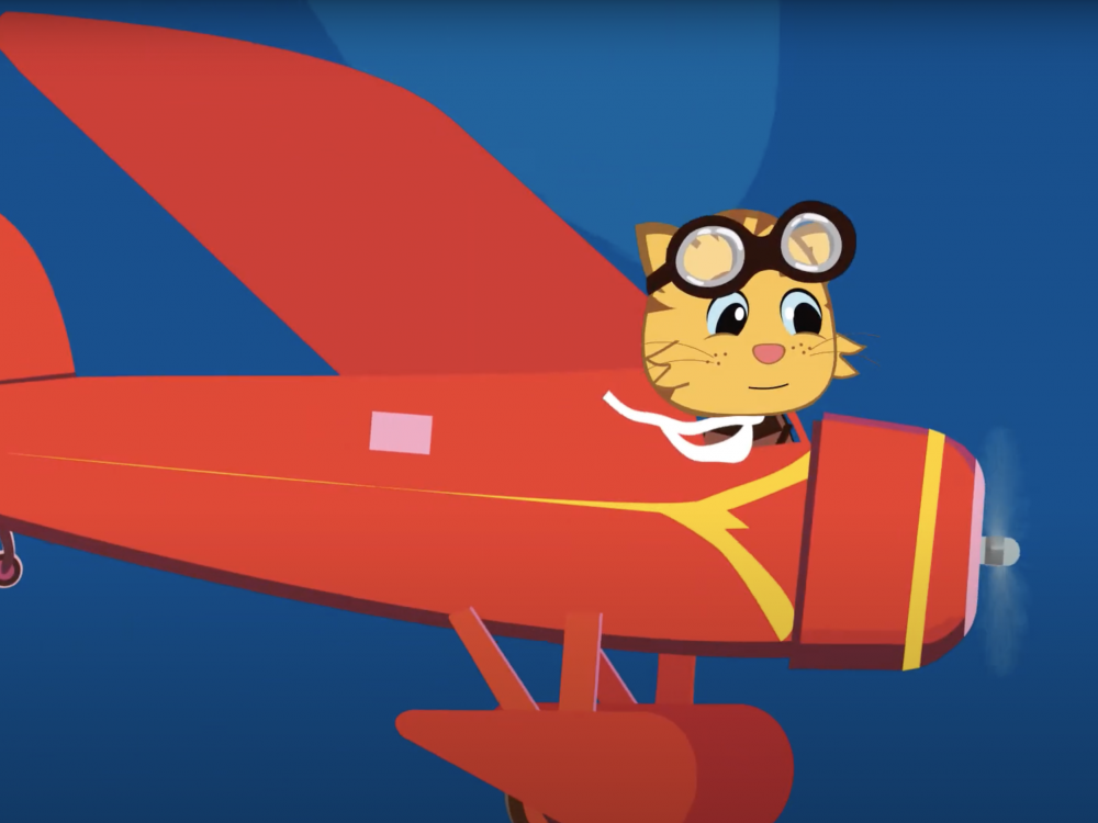 A little yellow cat flying in Amelia Earhart's red airplane.