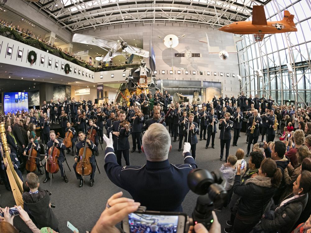 The U.S. Air Force Band performs in the museum with a large crowd of viewers in attendance.