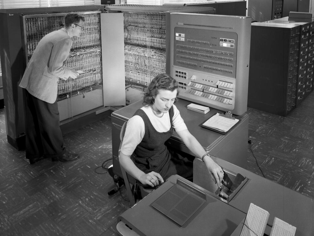 A woman makes calculations with a computer in the background.