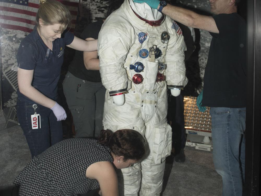 Buzz Aldrin's Apollo 11 spacesuit being moved out of the exhibit case in the "Apollo to Moon" gallery 