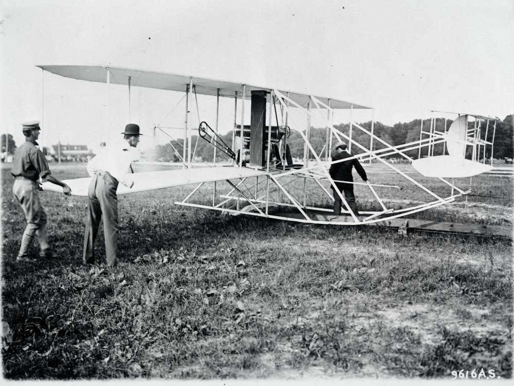 Black and white photograph of Wilbur Wright preparing his aircraft.