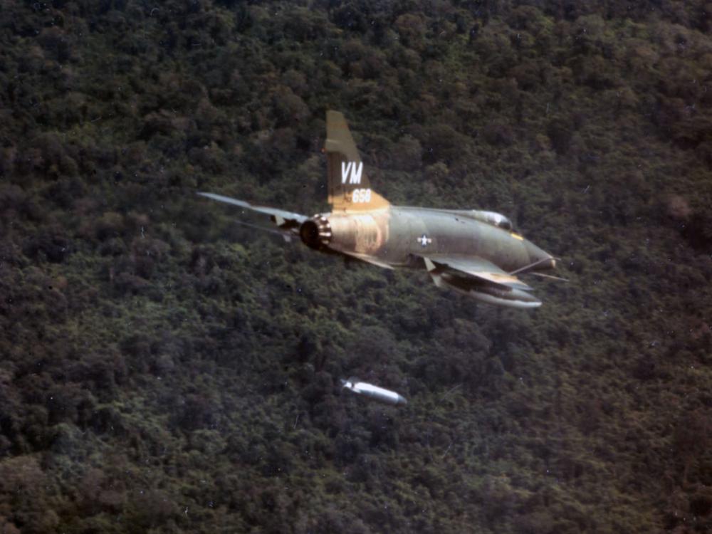 A F-100D aircraft of the 352nd Tactical Fighter Squadron dropping a napalm bomb near Bien Hoa, South Vietnam.