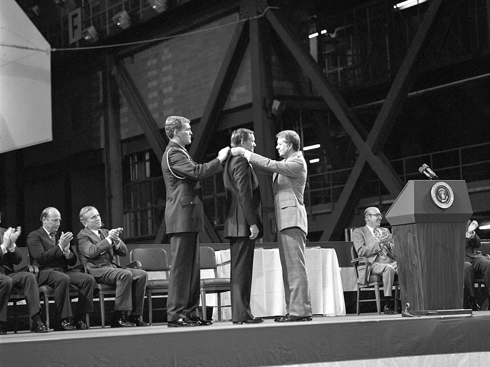 Jimmy Carter putting a medal around the neck of Neil Armstrong