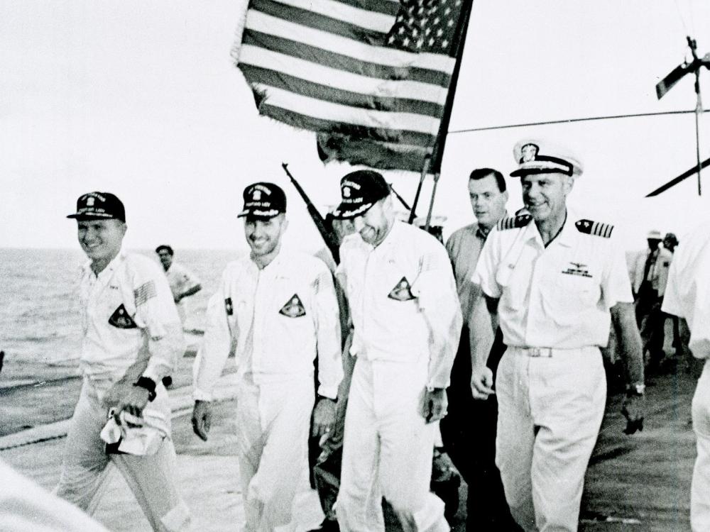 Apollo 8 astronauts and commanding officer of the recovery ship U.S.S. Yorktown walk the red carpet of the flight deck after splashdown recovery in the Pacific Ocean