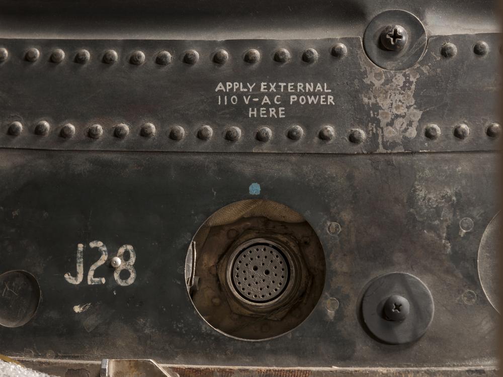 A close up of part of the exterior of the Friendship 7 spacecraft. A plug and notations can be seen.