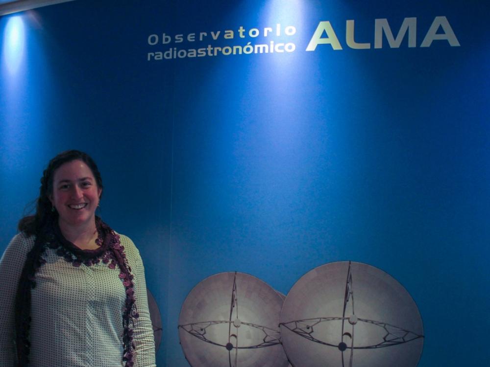 Image of Genevieve in front a sign for the ALMA observatory.