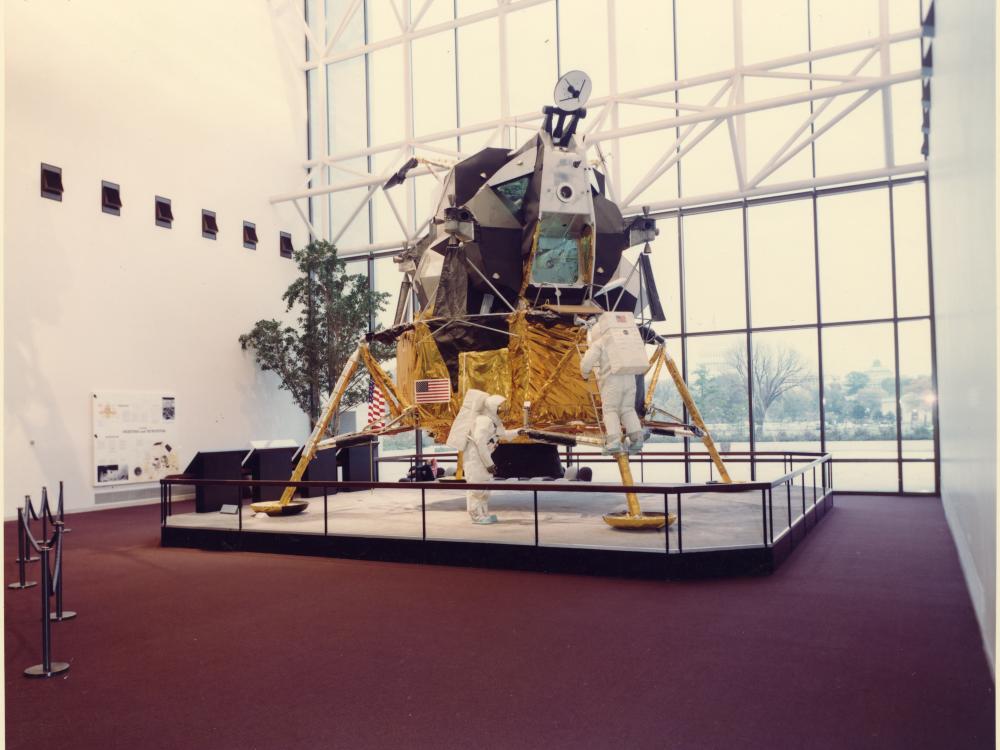 Lunar Module with protective railing on red carpet.