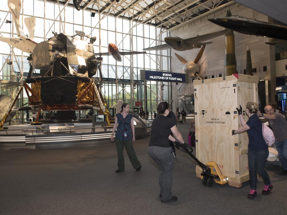 Gene Cernan's Apollo 17 spacesuit being moved out of the exhibit case in the "Apollo to Moon" gallery