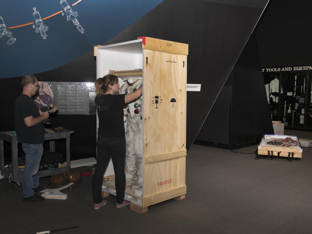 Buzz Aldrin's Apollo 11 spacesuit being moved out of the exhibit case in the "Apollo to Moon" gallery