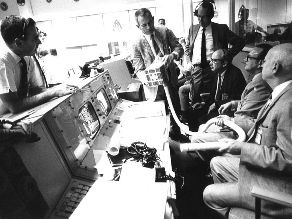 group of men around mission control desk