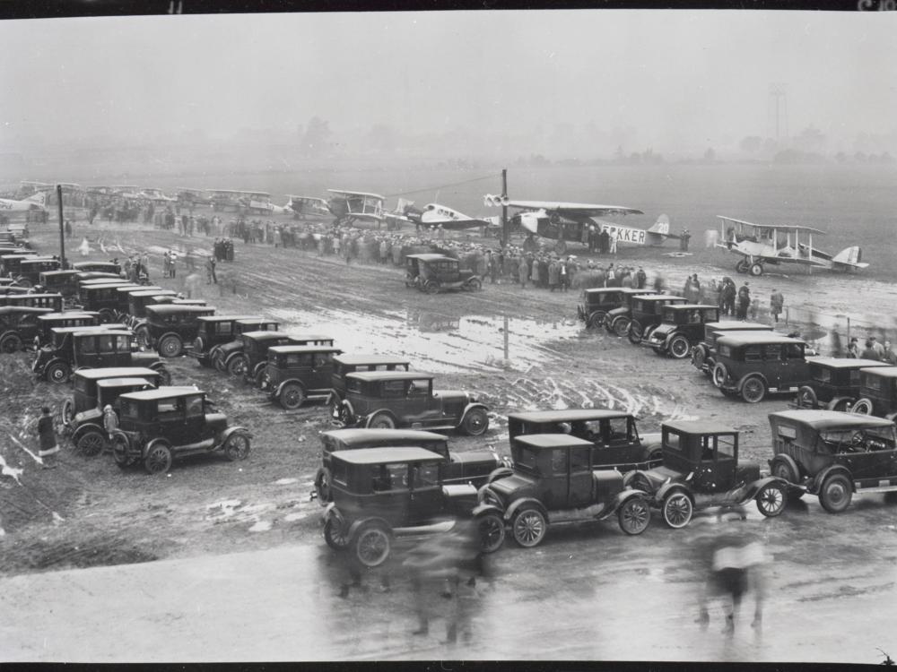 High level view of aircraft participating in the first Ford Commercial Airplane Reliability Tour lined up in rainy weather at the edge of the field 