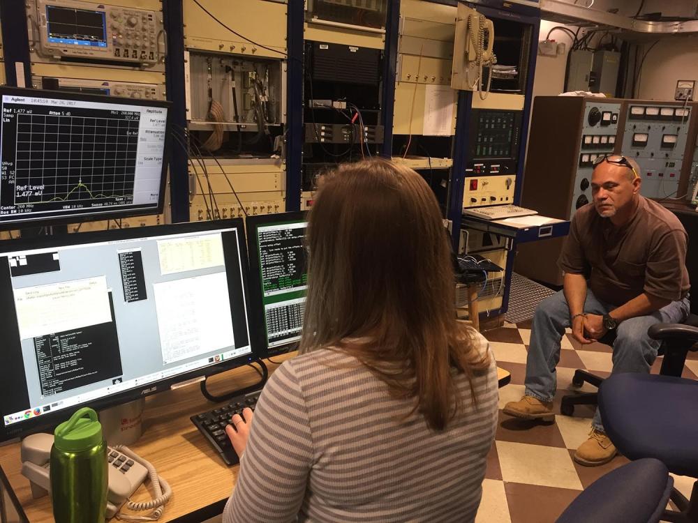 Woman enters in commands into a computer while a man looks on. 